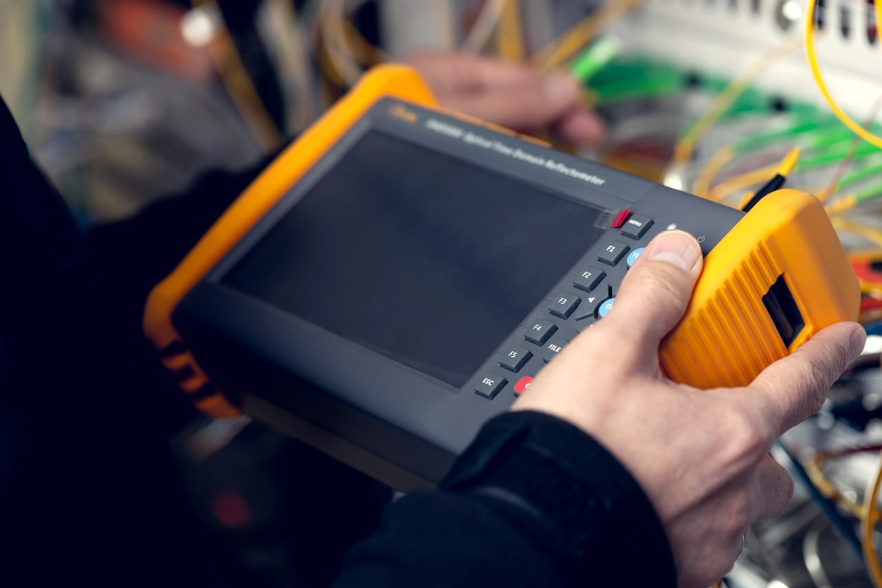 Technik drží měřicí přístroj OTDR před optickým rozvaděčem