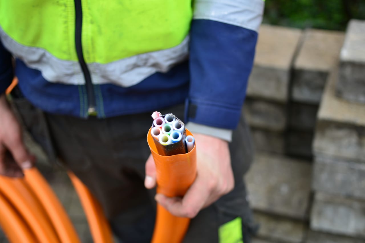Přeříznutá HDPE chránička s barevnými mikrotrubičkami v ruce montéra